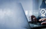 eine Person am Laptop, über dem digitale Symbole zu ISO‑Zertifizierung und Qualitätsmanagement eingeblendet sind.