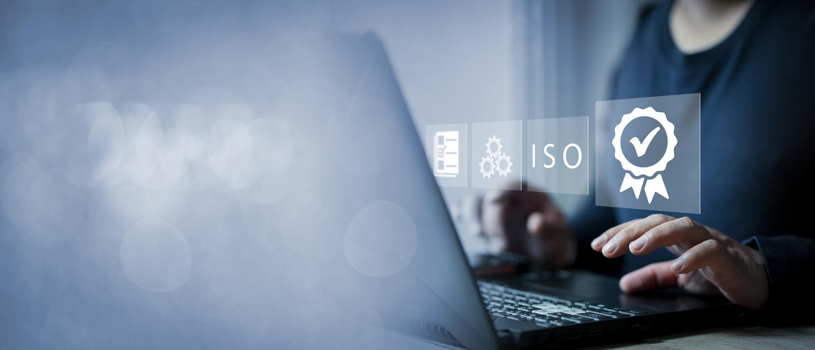 eine Person am Laptop, über dem digitale Symbole zu ISO‑Zertifizierung und Qualitätsmanagement eingeblendet sind.
